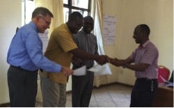 Wayne, Frank Tweheyo and Domnic Misolo (L to R) present a completion certificate to Eliya Musa, who also provided English to Swahili translation for the seminar.